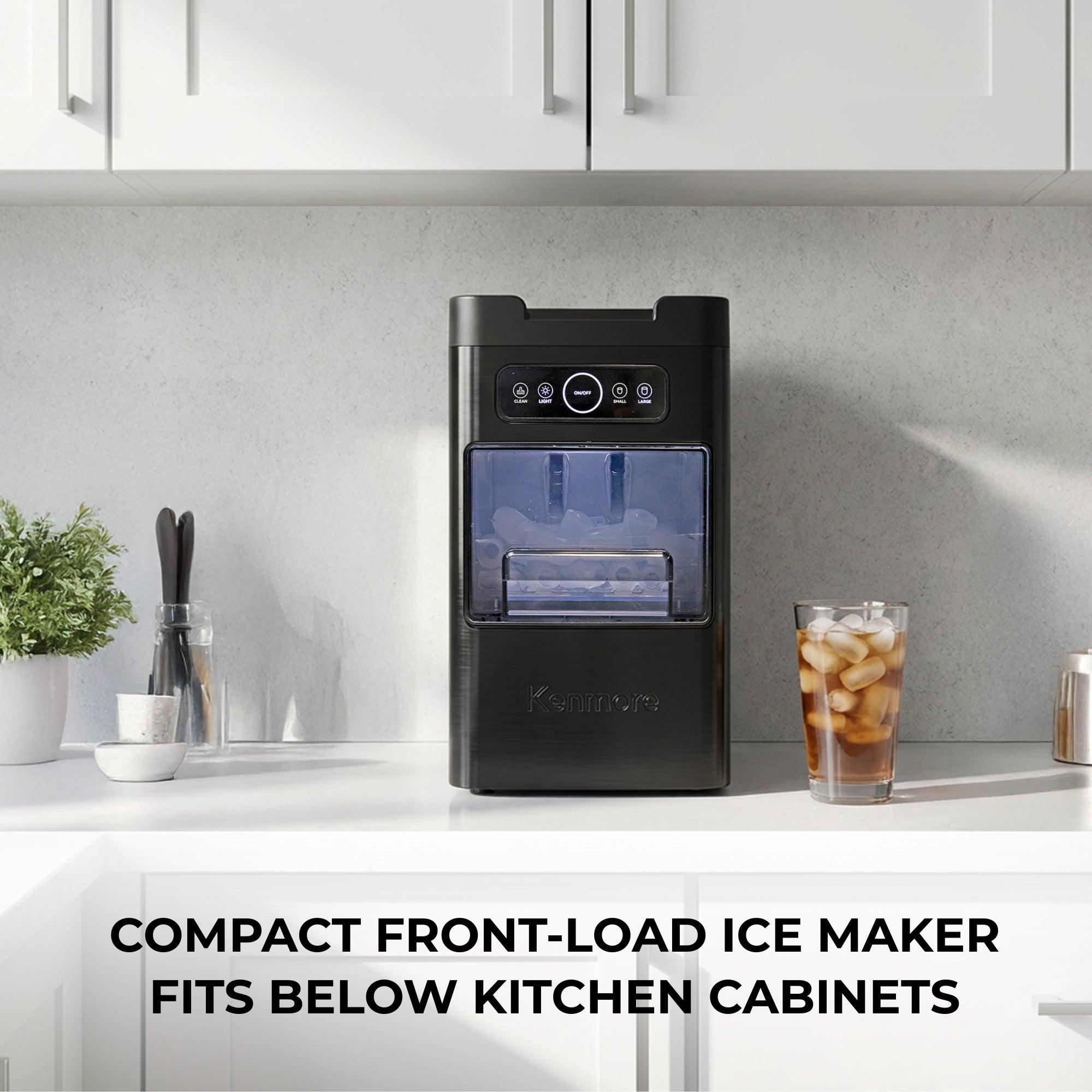 Kenmore front-load bullet ice maker on a white marble countertop with a glass of orange juice with ice to the right