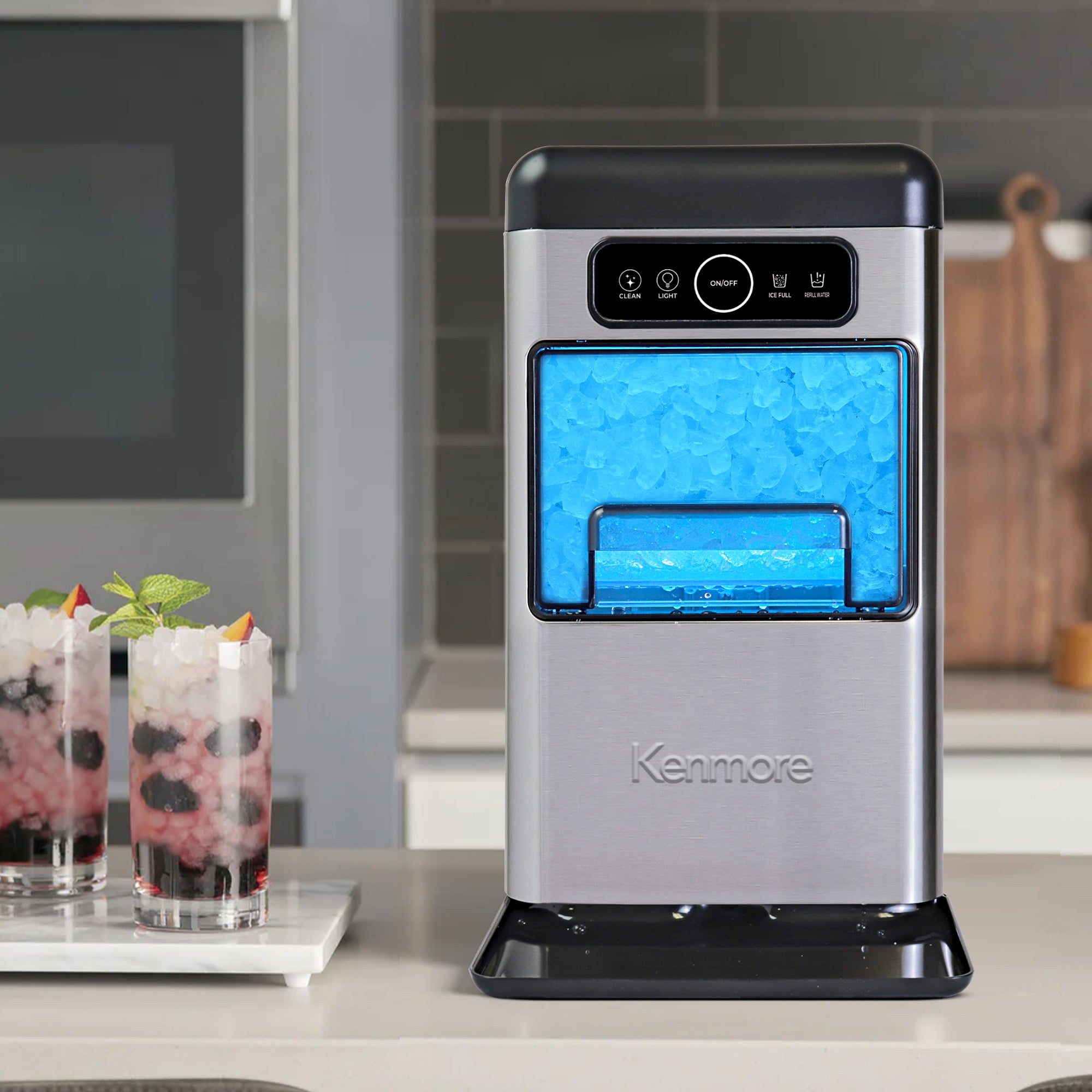 Kenmore front-load nugget ice maker on a beige countertop with two glasses of iced beverages to the left