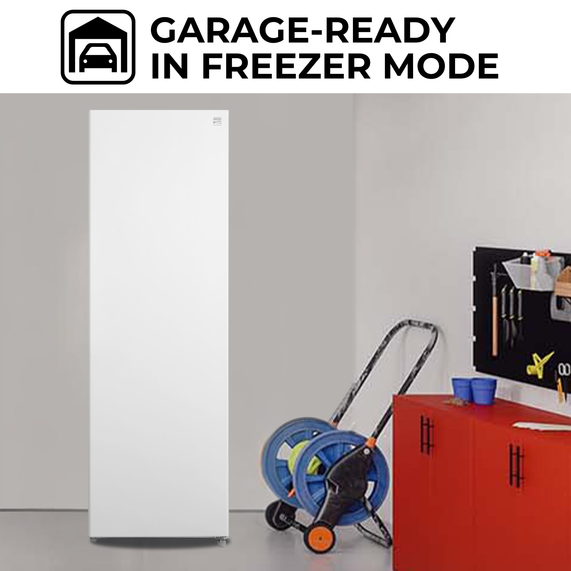 Kenmore convertible upright freezer/refrigerator, closed, in a garage with a red tool bench and lawn roller beside it. Text above reads, "Garage-ready in freezer mode"