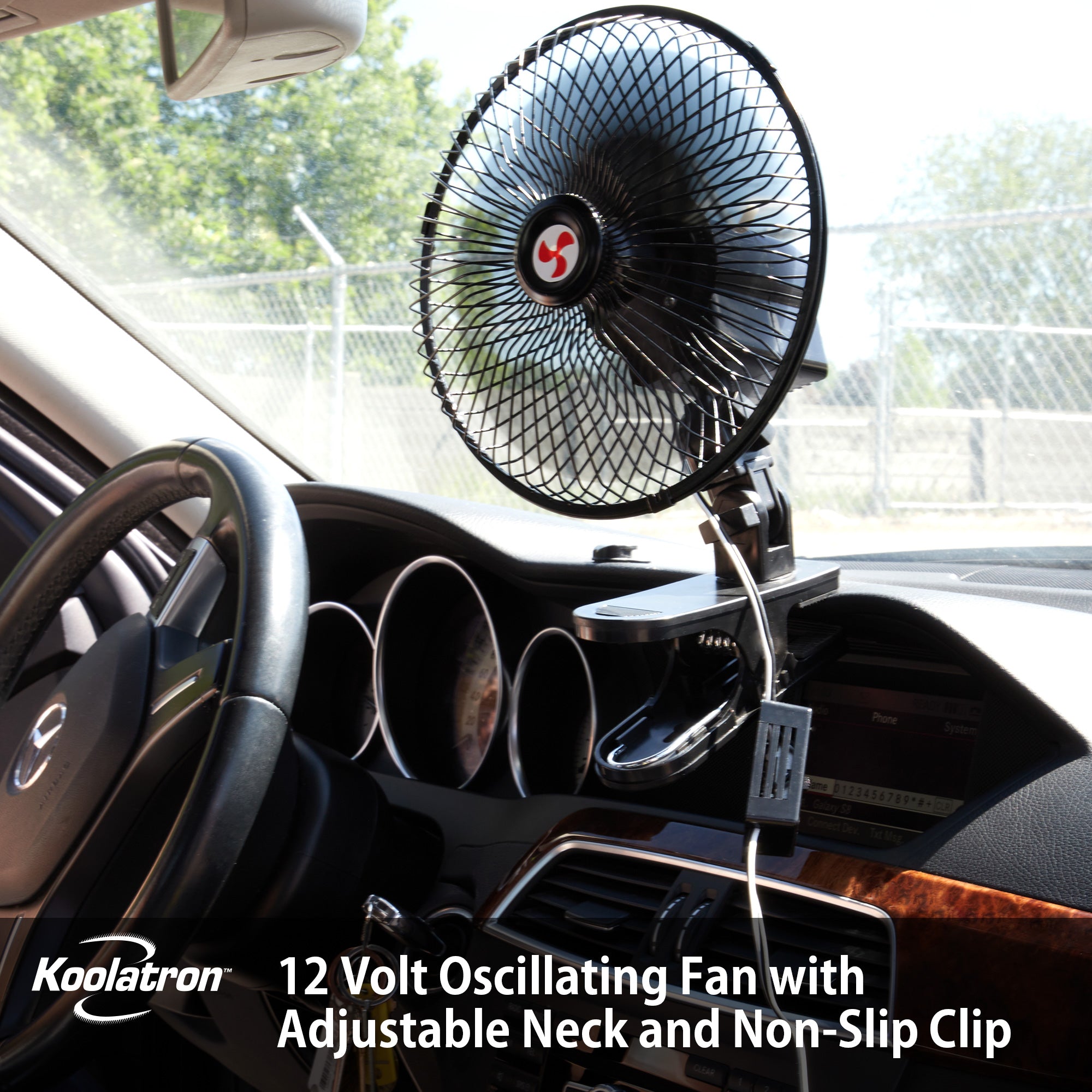 Lifestyle image of the 12V oscillating fan clipped to the dashboard of a vehicle with black and brown tortoiseshell interior. Text below reads, "Koolatron 12 volt oscillating fan with adjustable neck and non-slip clip"