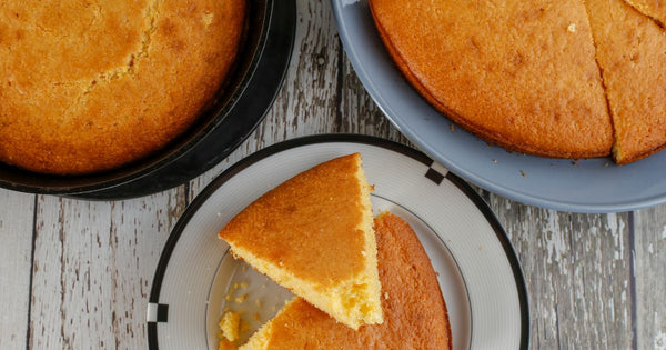 Closeup photo of round loaves and wedges of golden-brown cornbread on plates viewed from above