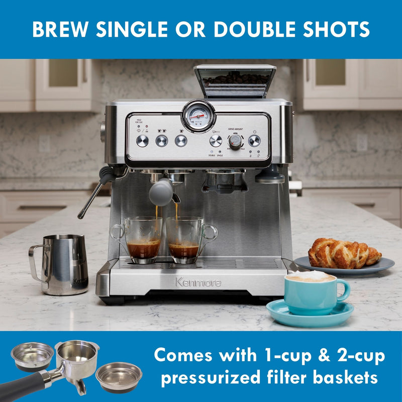 Kenmore semi-automatic espresso maker with espresso being extracted into two clear cups on a white marble countertop with the milk pitcher, a pastry, and a cappuccino in a light blue mug arranged around it. Text above reads, "Brew single or double shots," and text below reads, "Comes with 1-cup and 2-cup pressurized filter baskets" accompanied by an inset picture of a portafilter and 2 filter baskets.