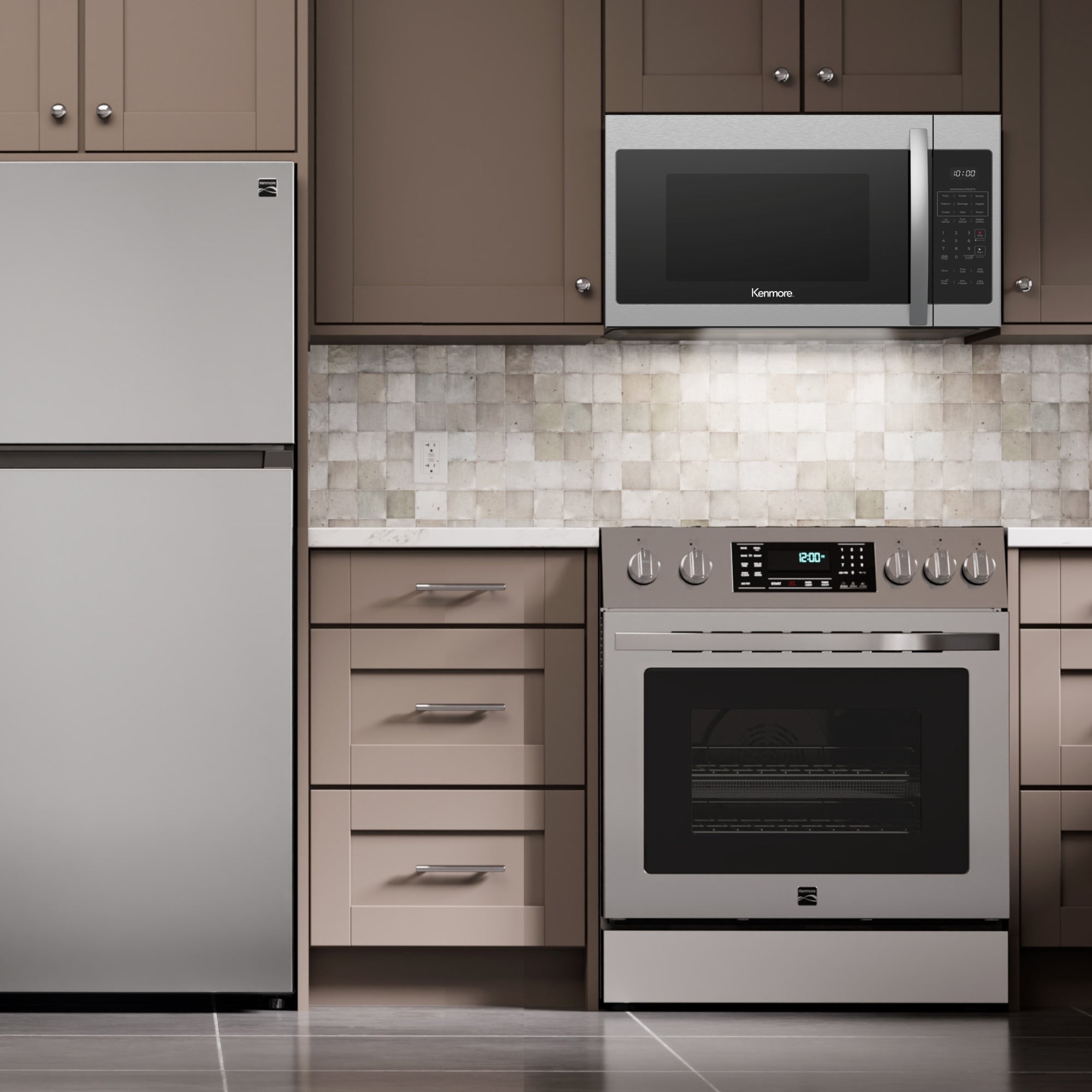 Kenmore over-the-range microwave installed in a taupe kitchen above a stainless steel range with a stainless steel top-mount refrigerator to the left.