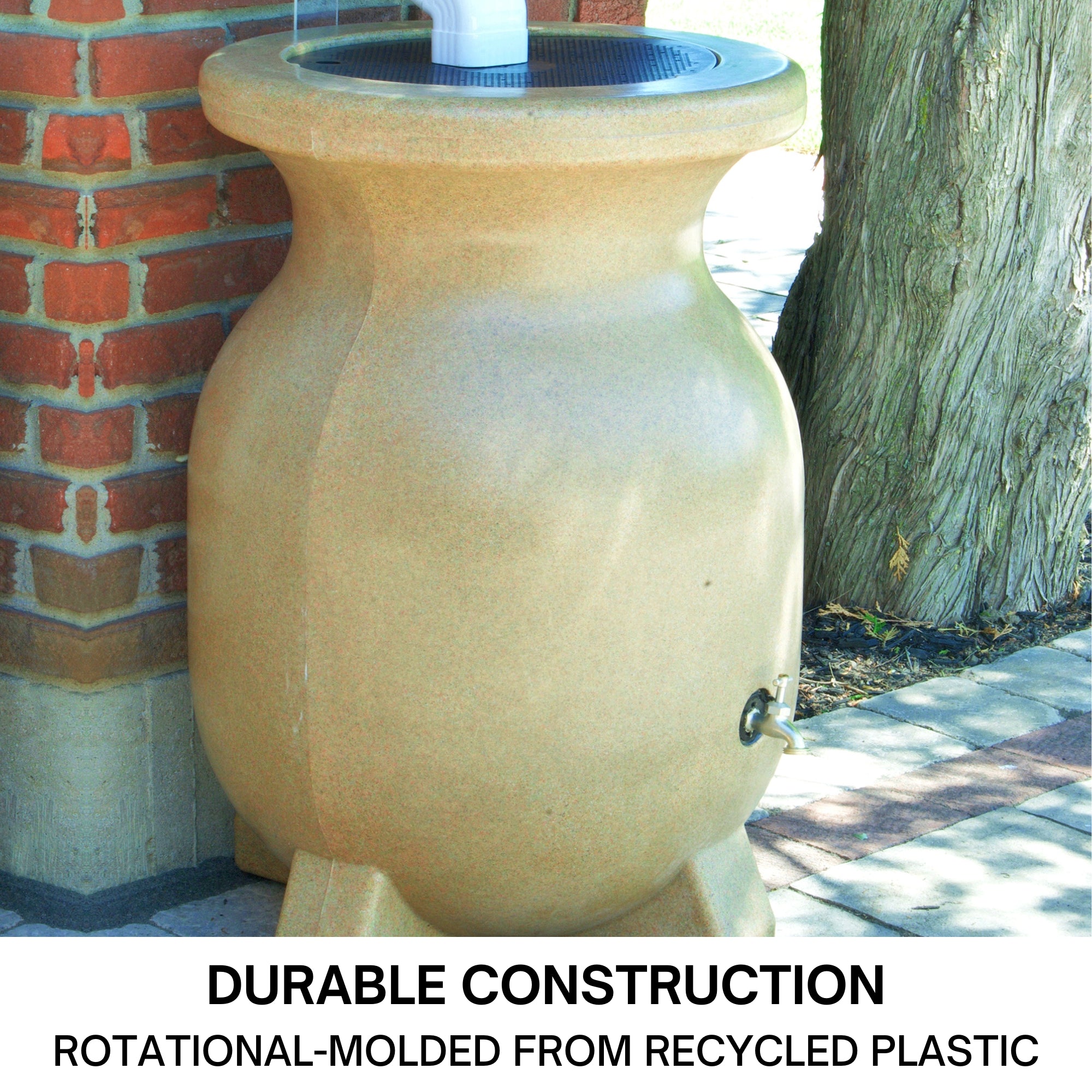 Koolscapes faux sandstone rain collector set up on a concrete path below a white downspout with a red brick wall, tree, and grass in the background. Text below reads, "Durable construction: Rotational molded from recycled plastic."