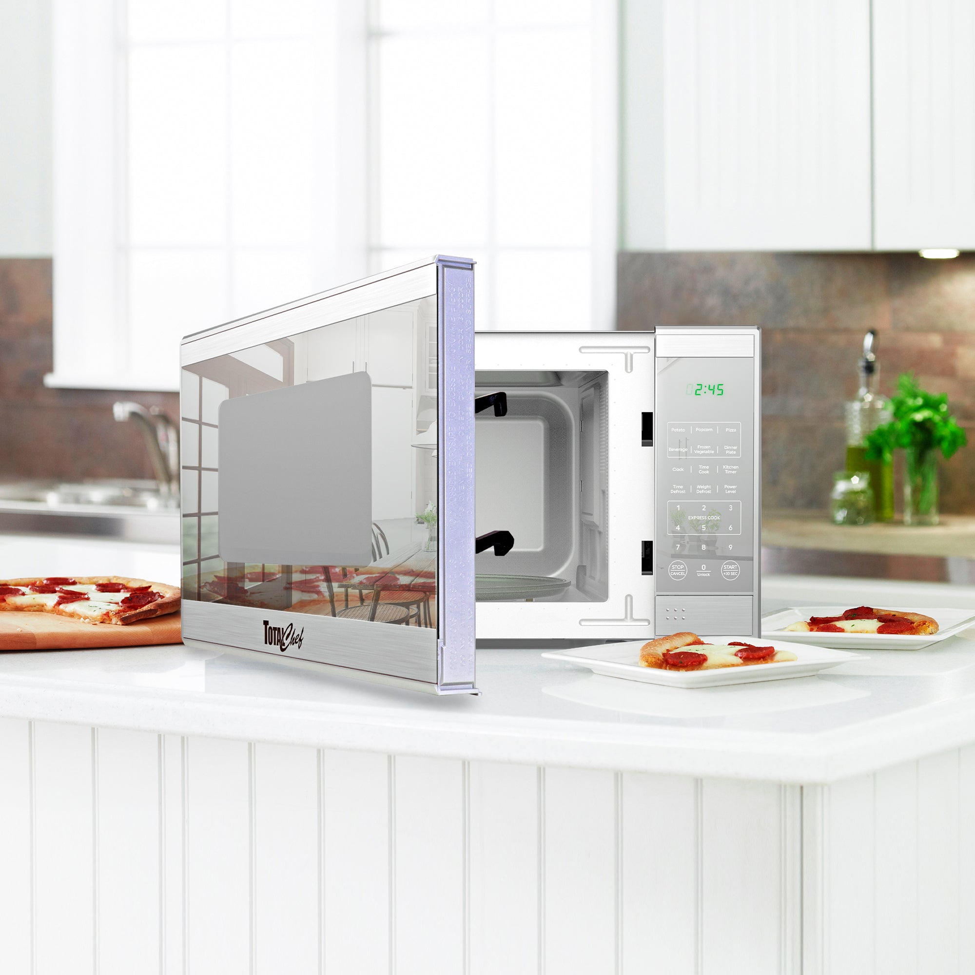 Total Chef stainless steel microwave, partly open, with slices of pizza on plates arranged around it on a white counter in a modern-looking kitchen