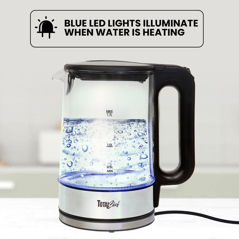 Total Chef cordless glass kettle full of boiling water on a white countertop. Text overlay reads "Blue LED lights illuminate when water is heating"