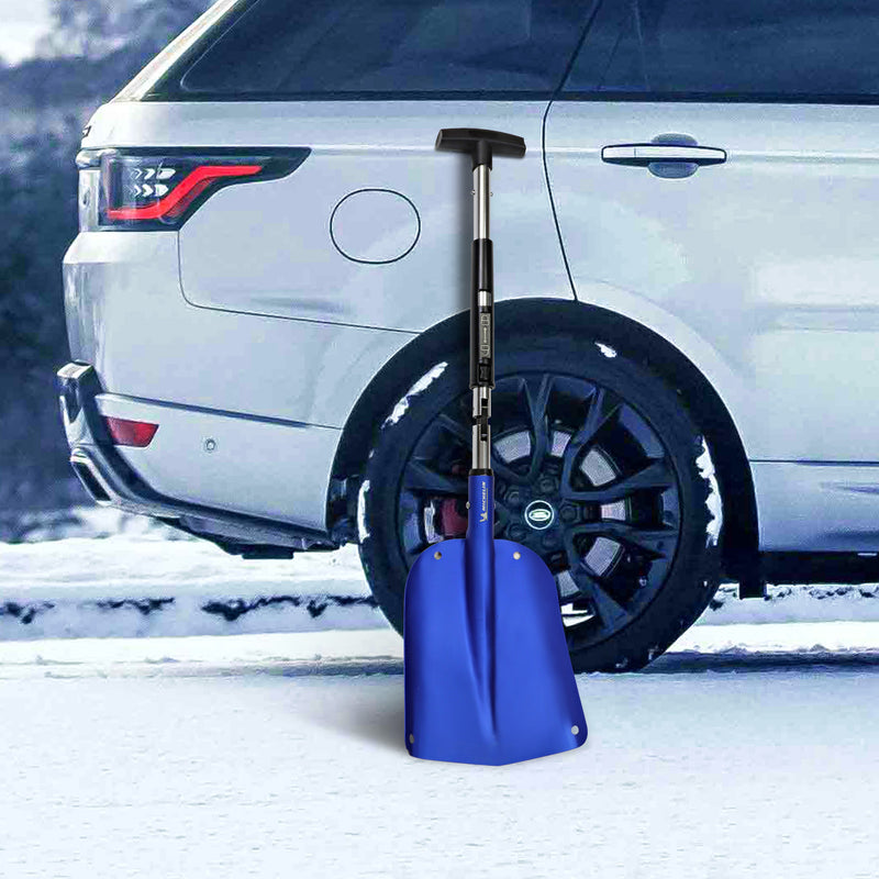 Lifestyle image of the utility shovel leaning against the rear passenger side of a white SUV on a snow-covered road