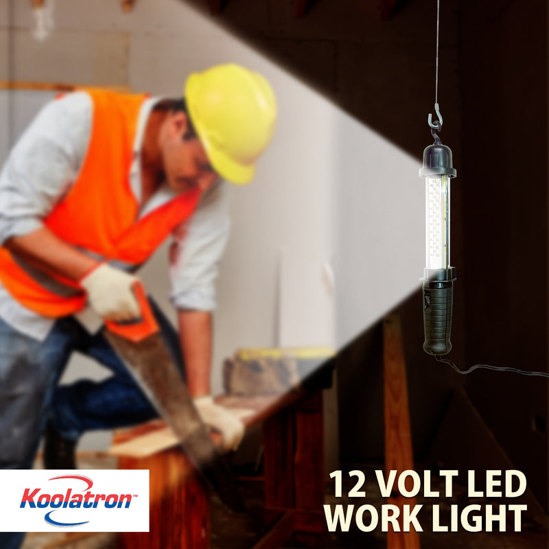 Lifestyle image of the 12V hanging work light illuminating a person with light skin and dark hair and mustache wearing jeans, white shirt, orange safety vest, yellow hard hat, and white safety gloves, sawing a piece of wood. Text overlay reads, "Koolatron 12 volt LED work light"