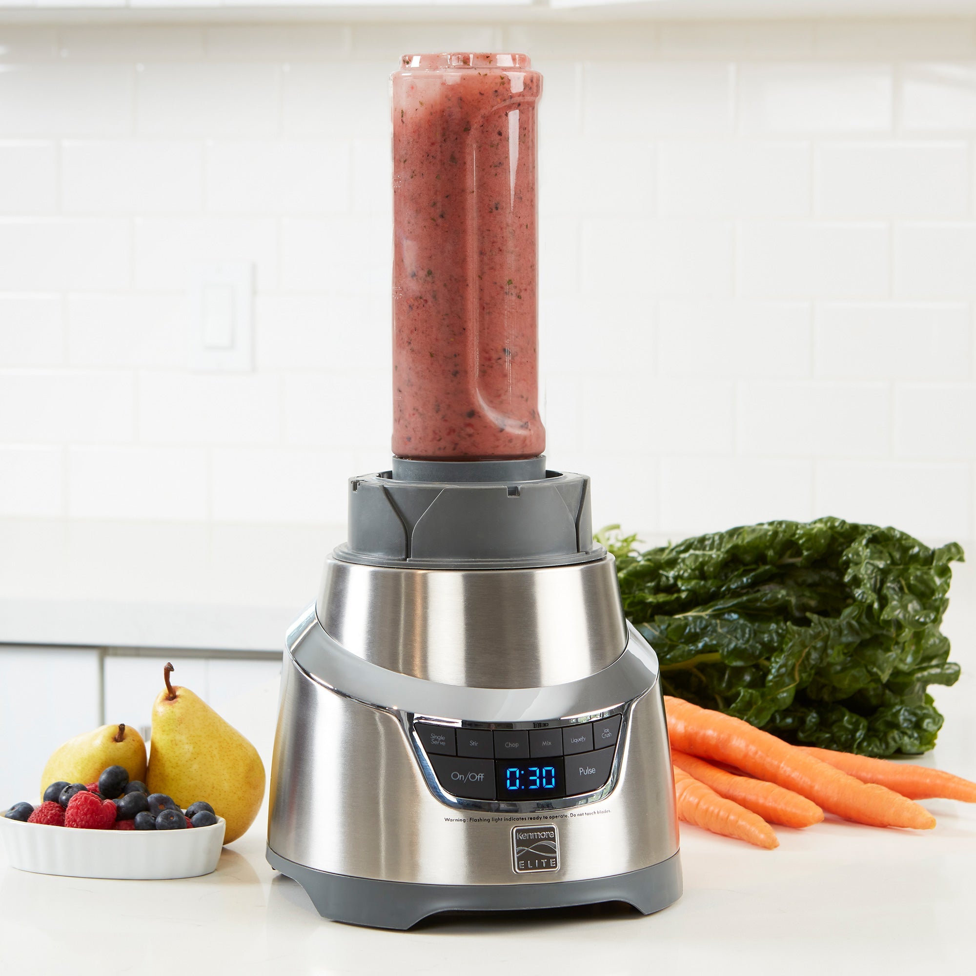 Kenmore Elite 1.3 HP blender on white counter with a smoothie blended in the single-serving cup and fruits and vegetables beside