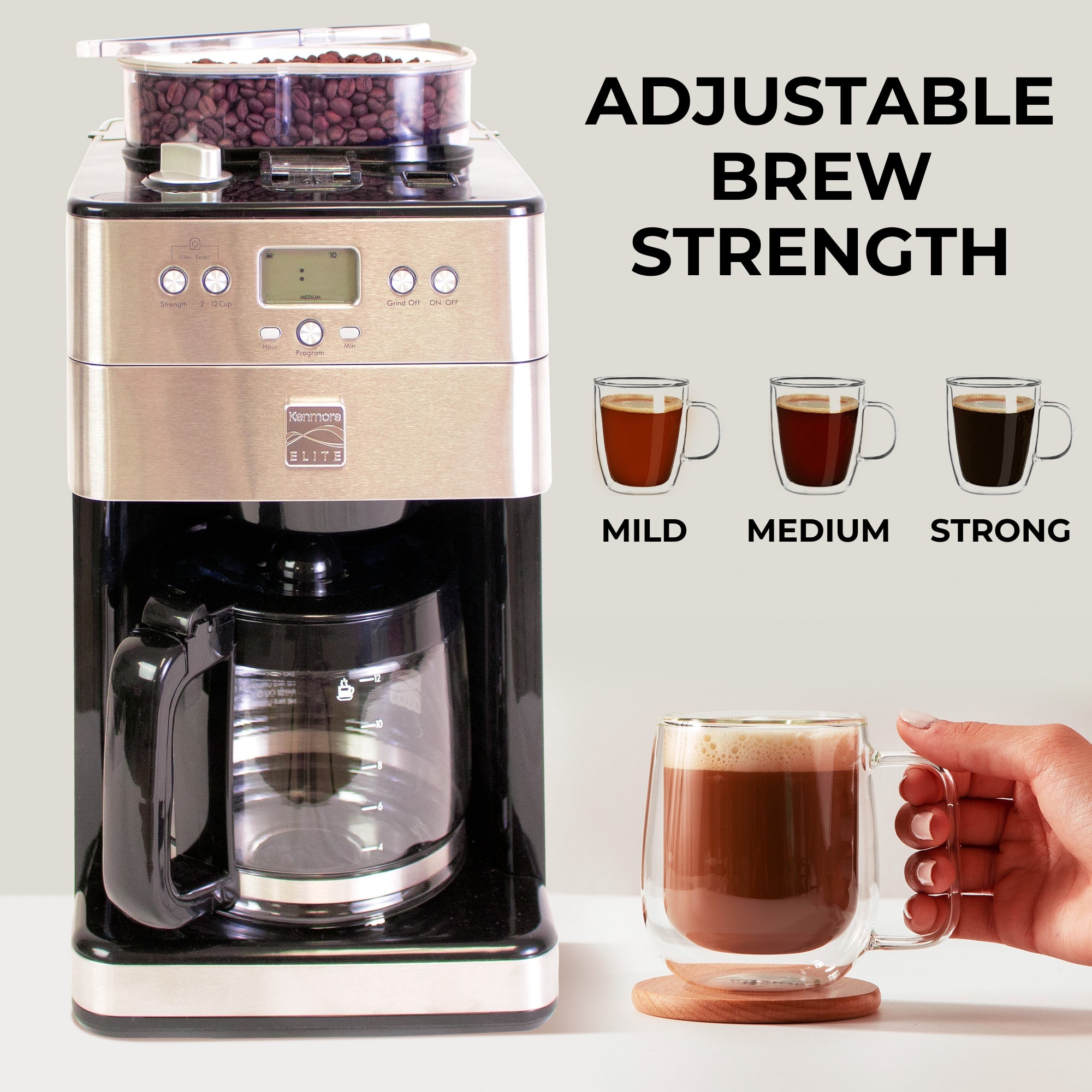 Kenmore grind and brew coffee maker and a hand holding a clear glass mug of coffee. Above the mug are three drawings of clear mugs holding coffee of various strengths, labeled mild, medium, and strong. Text above the drawings reads, "Adjustable brew strength"