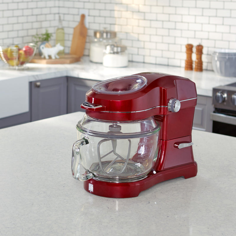 Lifestyle image of red Elite Ovation tilt-head stand mixer on a light gray kitchen counter with gray cupboards in the background